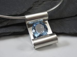 A silver pendant with a blue crystal