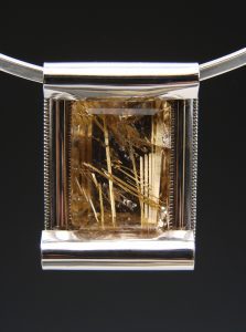 A silver pendant with a light-yellow crystal