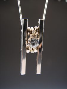 A clear pendant connected to silver rods