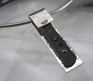 A silver pendant with a black slab