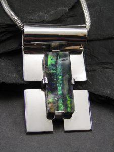 A silver pendant with a blue stone