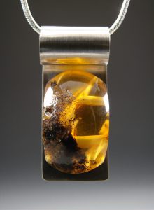 A silver necklace with a yellow gem