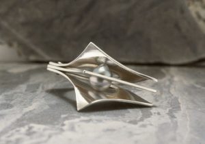 A silver clamp with a pearl