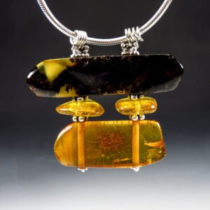 A silver necklace with a black and yellow pendant